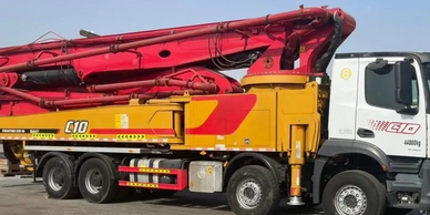 A large yellow and red concrete pump truck parked outdoors.