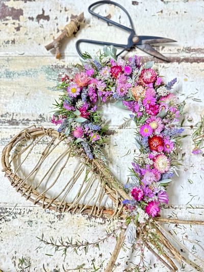 Floral wreath in progress with scissors and twine.