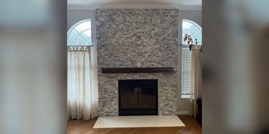 Modern stone fireplace with wooden mantel.