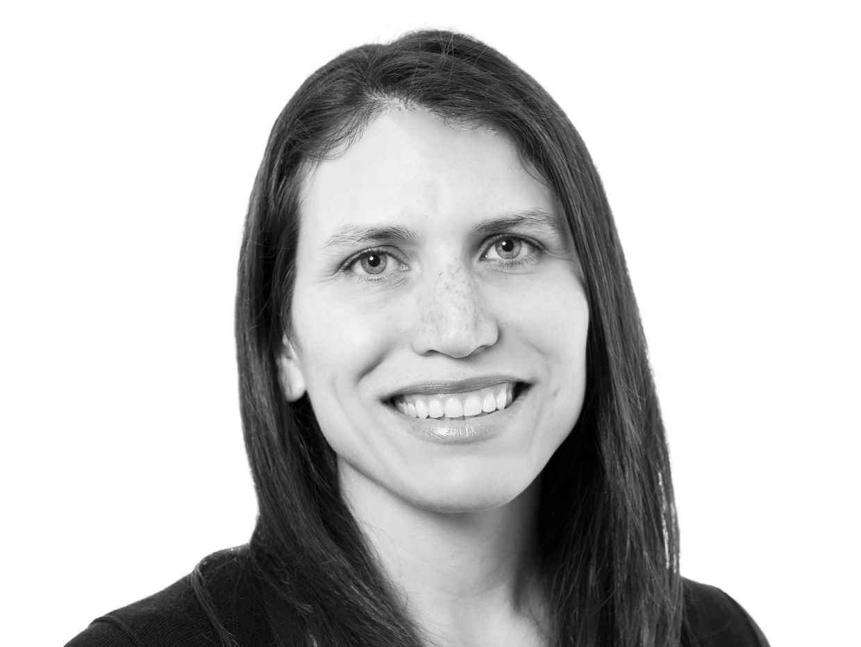 Black and white headshot of a smiling woman with straight hair.