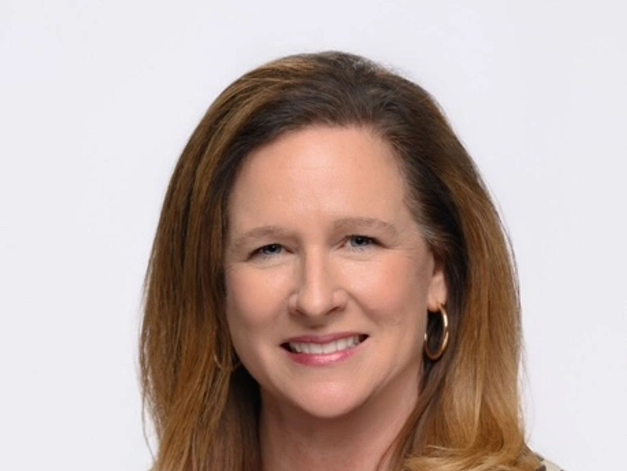 Smiling woman with light brown hair against a white background.