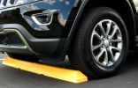 A car tire resting against a bright yellow parking curb.