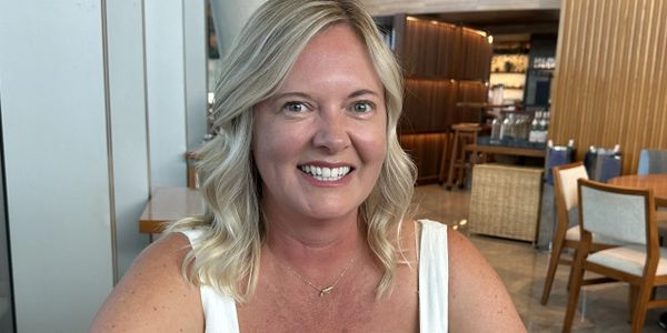 Smiling woman with blonde hair sitting in a stylish restaurant.
