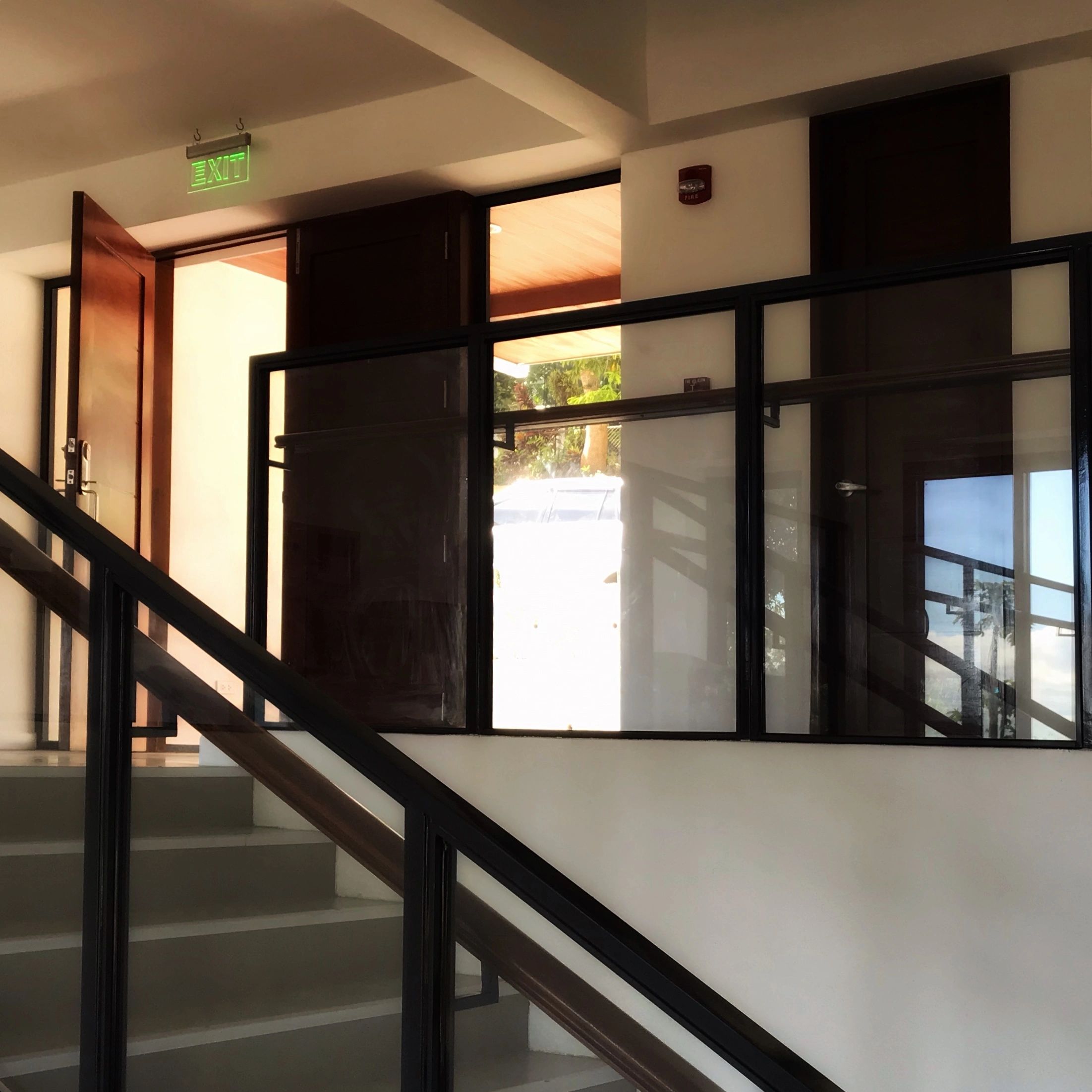 Staircase with glass railing leading to an open exit door with natural light.