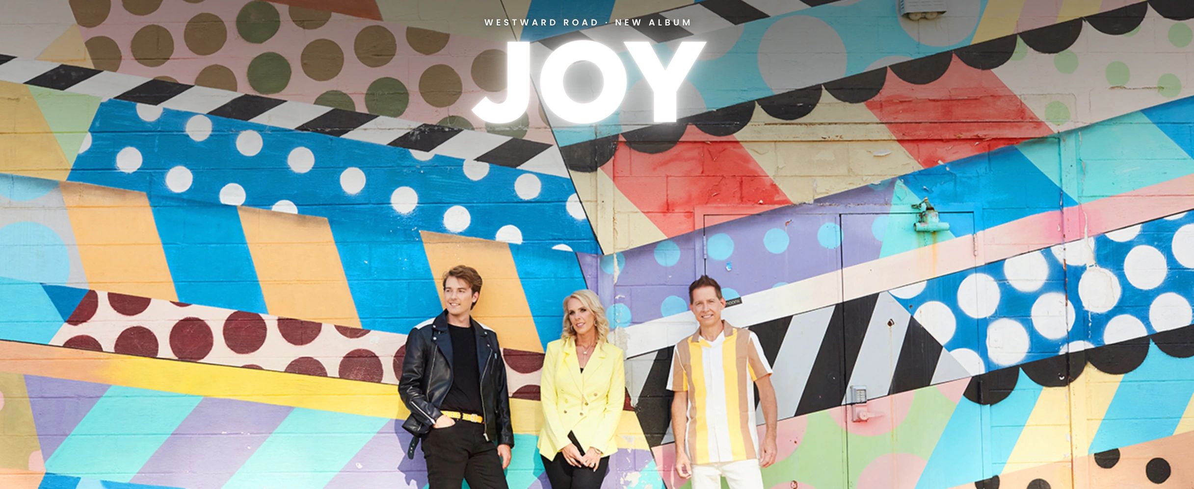 Colorful mural with three smiling people posing in front.