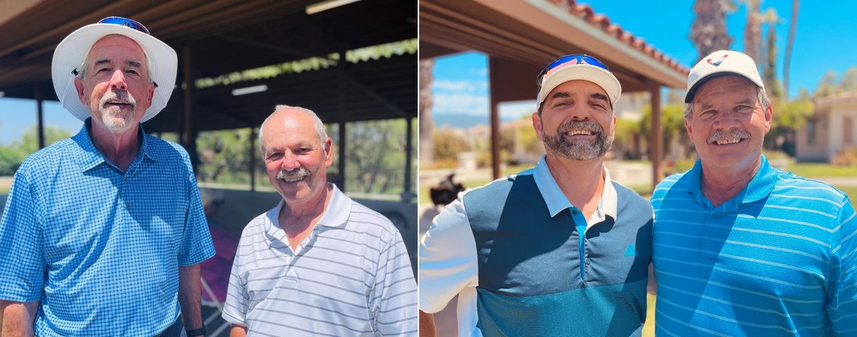 Four men smiling outdoors, dressed casually in golf attire under sunny skies.