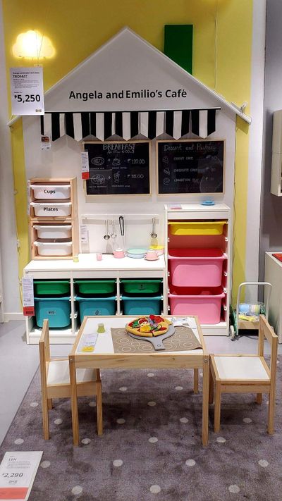 Children's play café setup with table, chairs, and colorful storage bins.