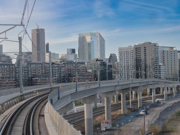 Train du REM circulant sur un viaduc en direction du centre-ville de Montréal

