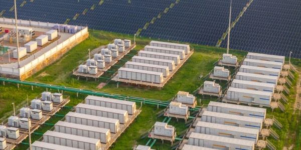Aerial view of an energy storage facility with solar panels in the background.
