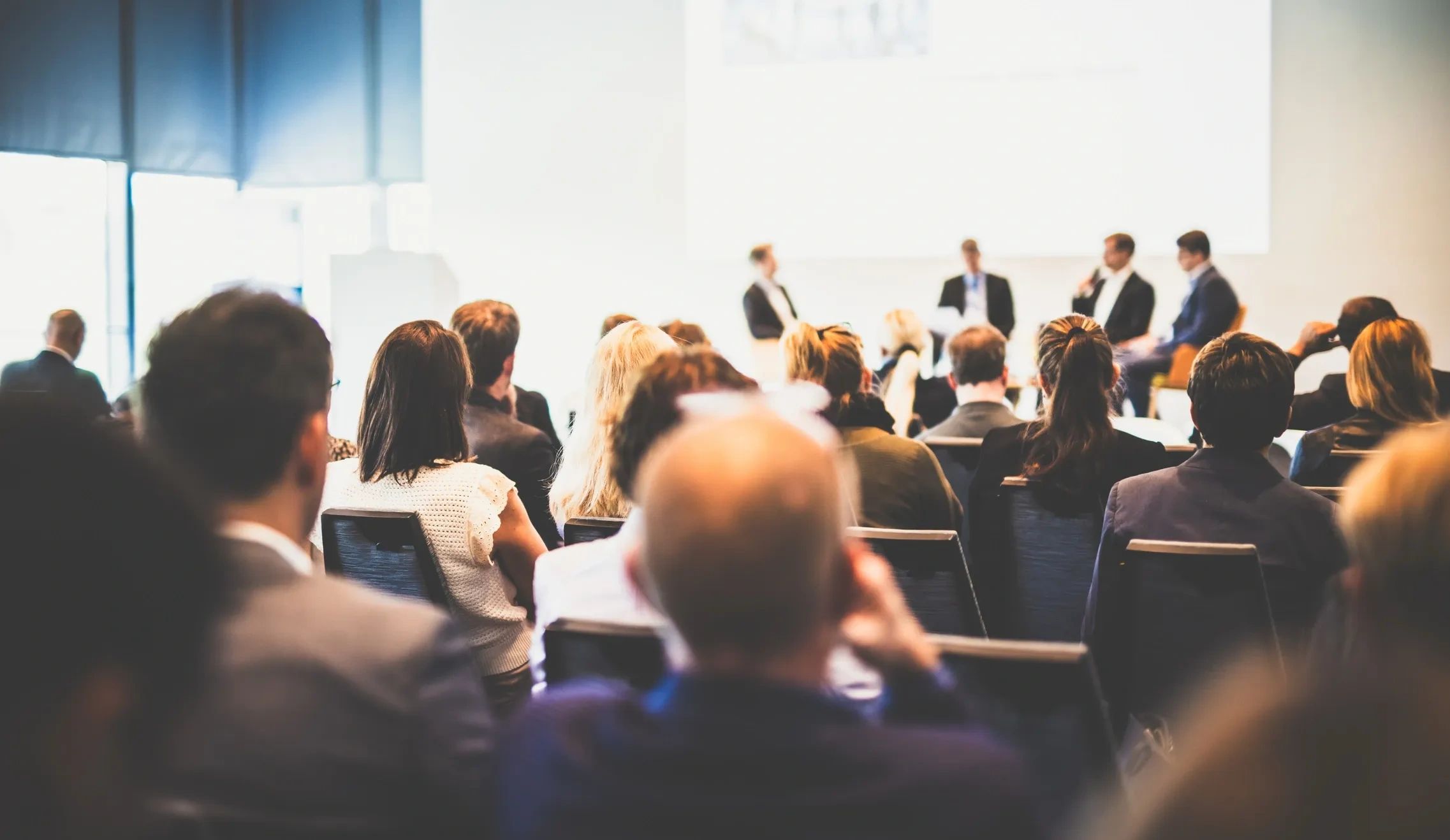 Audience attentively listening to a panel discussion in a conference room.