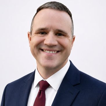 Smiling man in a suit and tie against a plain white background.