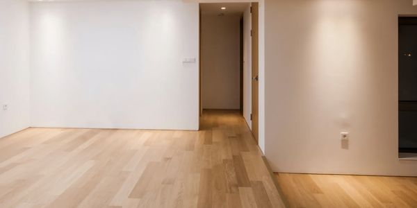 Empty room with light wooden flooring and white walls.