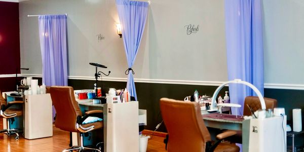Modern nail salon with cozy brown chairs and soft blue curtains.