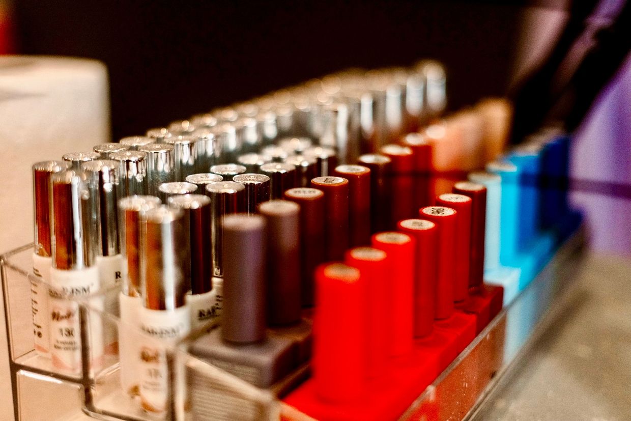 Rows of colorful nail polish bottles arranged in a clear acrylic holder.