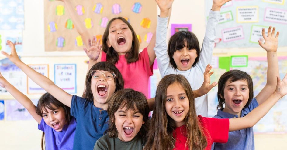 Students smiling and putting their hands up.