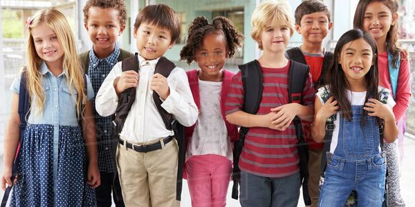 A group of diverse children smiling with backpacks, ready for school.