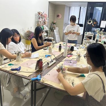 A group of women crafting floral arrangements together at a table.
