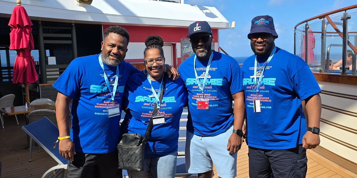 Group of four people posing on a cruise ship, all wearing matching blue shirts.