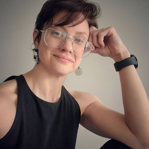 Person with glasses and a black sleeveless top smiling gently.