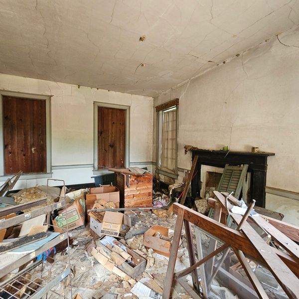 An abandoned room cluttered with broken furniture and cardboard boxes.