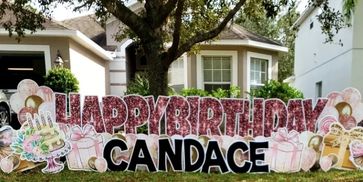 Outdoor birthday display saying Happy Birthday Candace with cake and gifts.