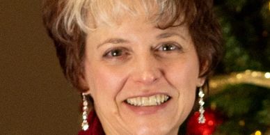 Smiling woman with short hair and dangling earrings.