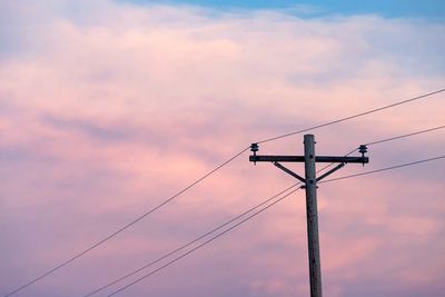 Utility pole silhouetted against a pastel sunset sky.