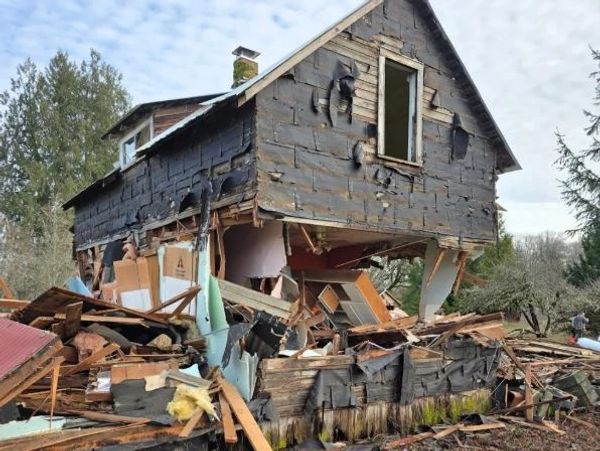 A severely damaged house with its upper floor partially collapsed and charred walls.