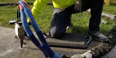 Concrete raising in action depicting injection gun and hose