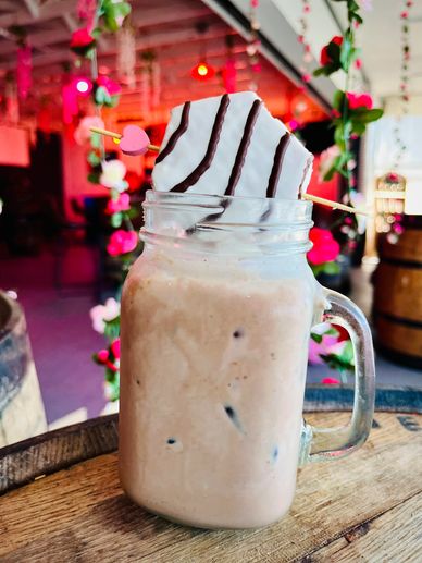 Iced coffee with chocolate cookie on top in a glass jar.