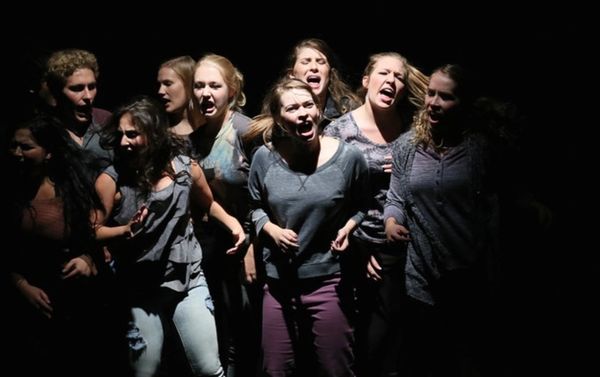 Group of people expressing intense emotions under spotlight.