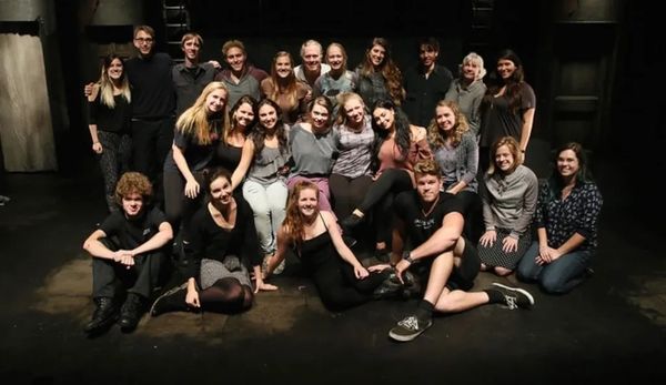 Group of people posing on a dark stage.