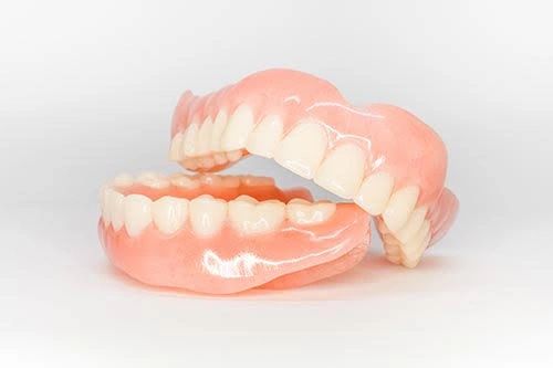 A set of upper and lower dentures on a white background.