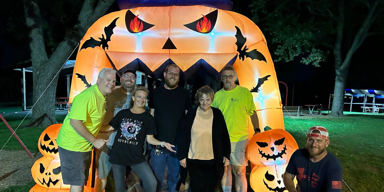 Group of people posing in front of a large inflatable Halloween decoration at night.
