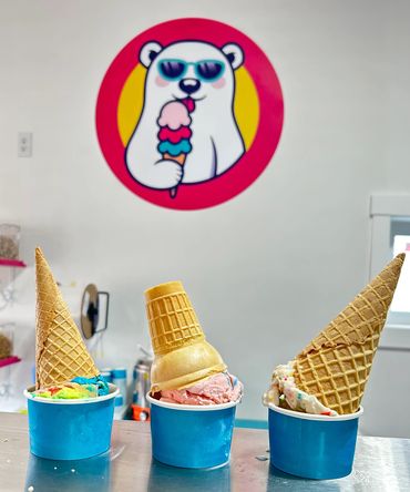 Three colorful ice cream cups with cones, under a cool polar bear mural.