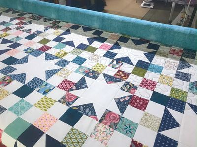 Image of a multi color quilt on a long arm machine.