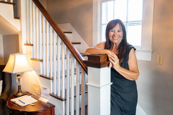 Woman in black dress smiling holding staircase rail