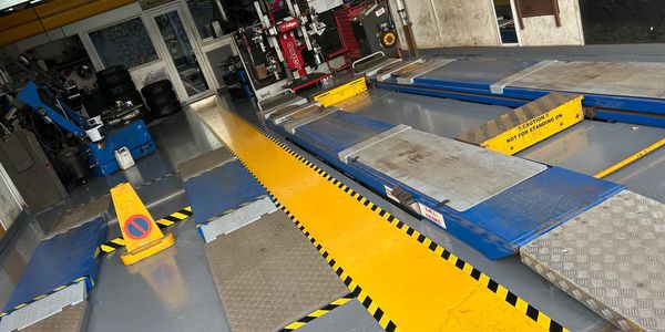 Empty vehicle inspection bay with bright yellow safety markings and equipment.