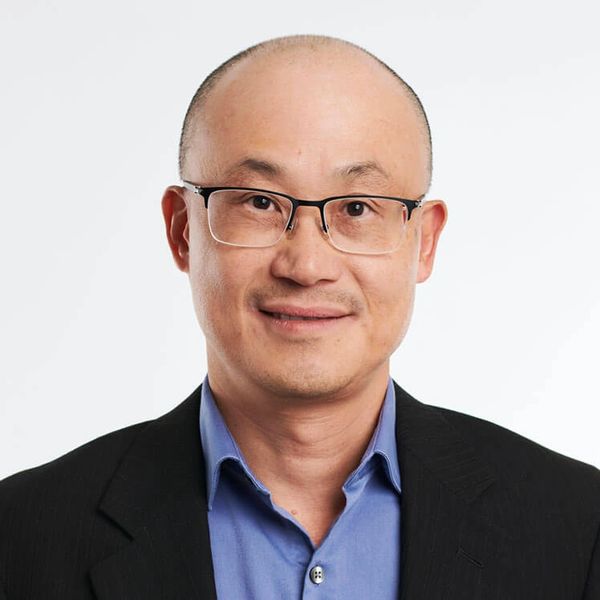 Smiling man with glasses in business attire against a white background.