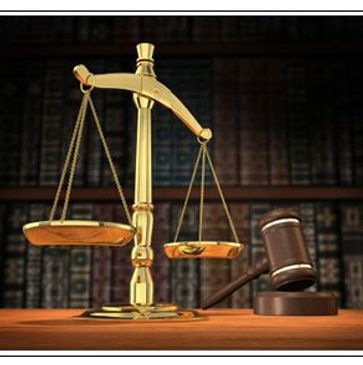Golden justice scales and wooden gavel on a desk with legal books in background.
