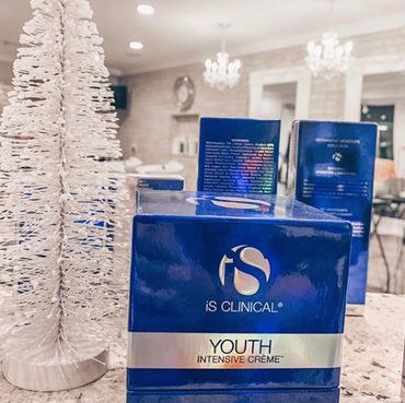 iS Clinical Youth Intensive Creme product packaging next to white decorative trees.