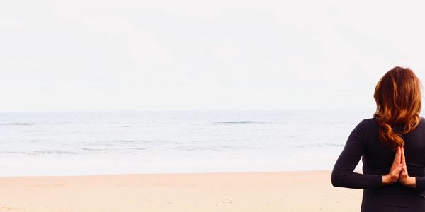 Rosanne on the beach doing Namaste