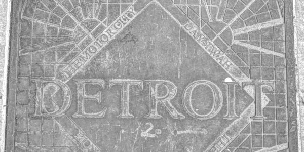 Stone engraving with the word Detroit and surrounding text.