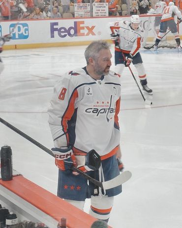 A hockey player in a Washington Capitals jersey warming up on the ice.