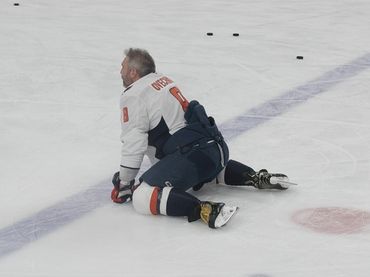Hockey player kneeling on the ice during practice.