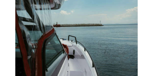 Side view of a boat on calm water with distant dock.