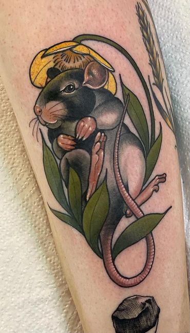 Tattoo of a rat with yellow flower and leaves.