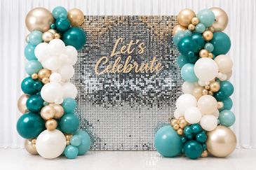 Elegant balloon arch with teal, white, and gold colors around a sparkling backdrop.