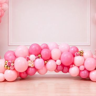 Pink balloon arch decorated with gold accents and flowers.