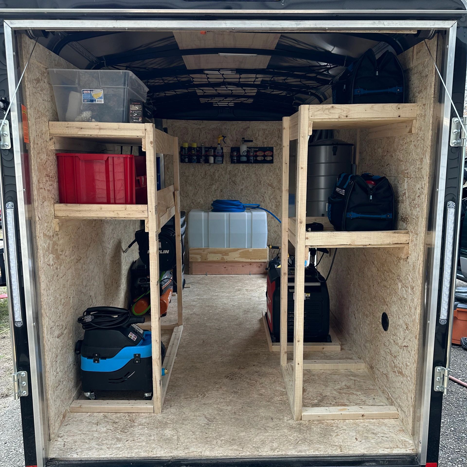 Organized storage with wooden shelves and equipment inside a trailer.